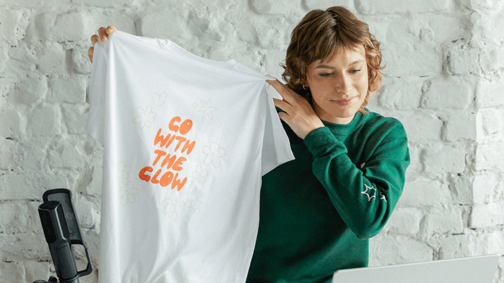 Sell custom merch to your followers A woman showing a custom made t-shirt to the camera.