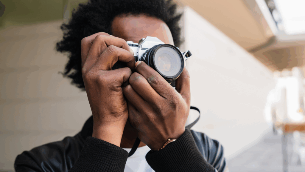 Sell photos online A man is capturing an image with a camera, focused on his subject in an outdoor setting.