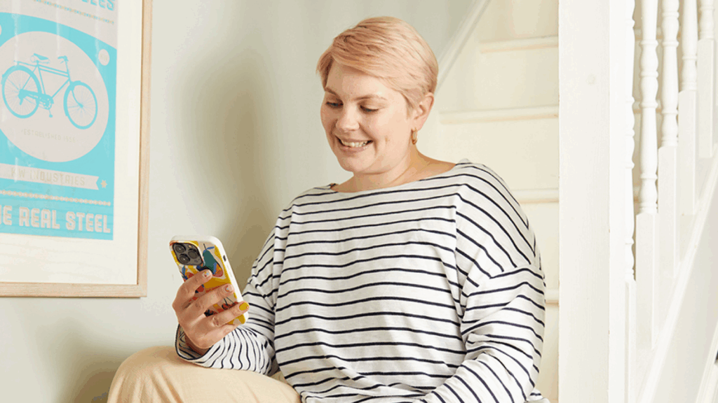 Social media management – Manage posts and grow followings A woman sitting on a stairway, holding a cell phone and looking thoughtfully at the screen.