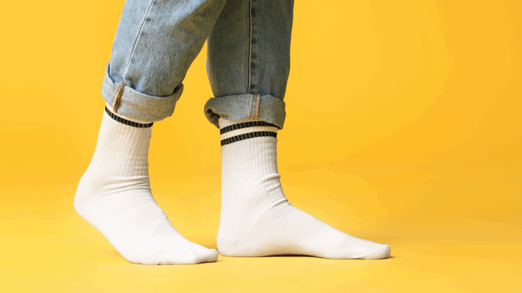 Socks Etsy shop ideas A person wearing white socks paired with blue jeans stands casually.