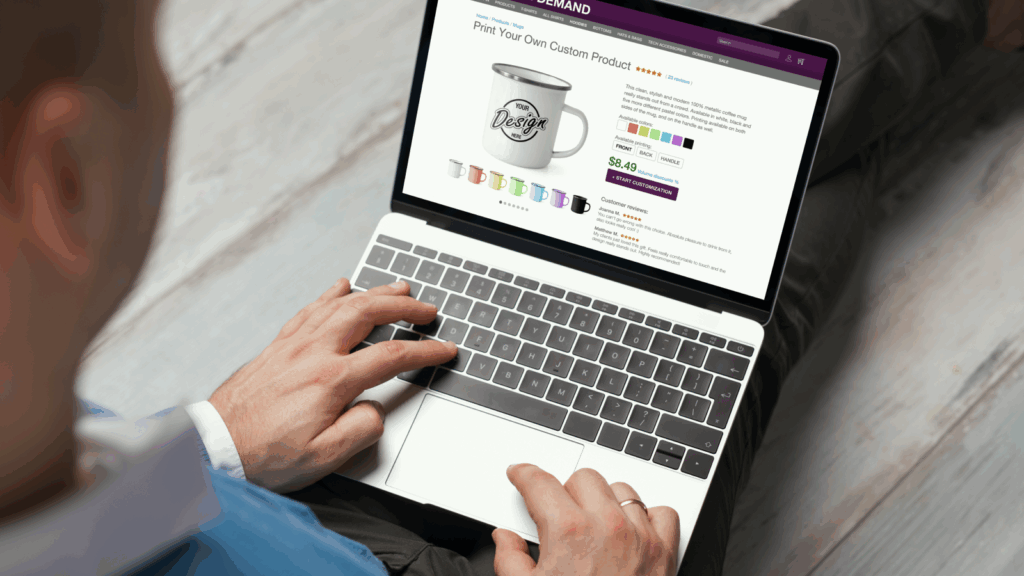 Start an online store with Print on Demand A man is seated at a desk, using a laptop to browse a website on the screen.