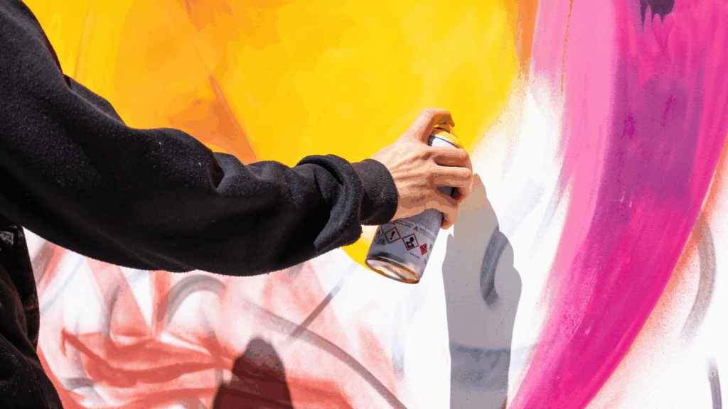 Styles and subjects A person spray paints a wall, creating vibrant colors and patterns.