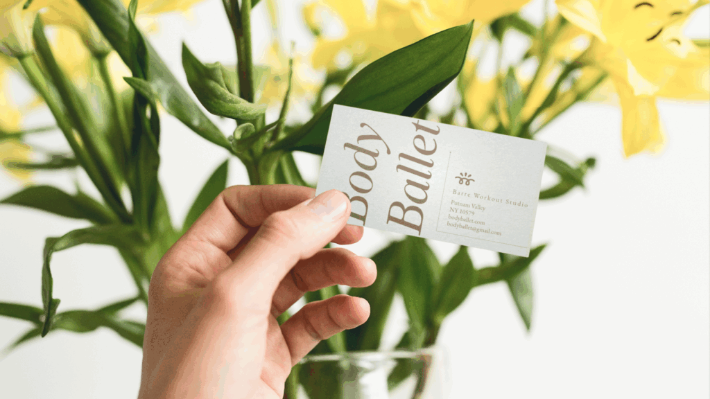 Vertical vs horizontal business cards A woman is holding a “Body Balley” business card with yellow flowers in the background.