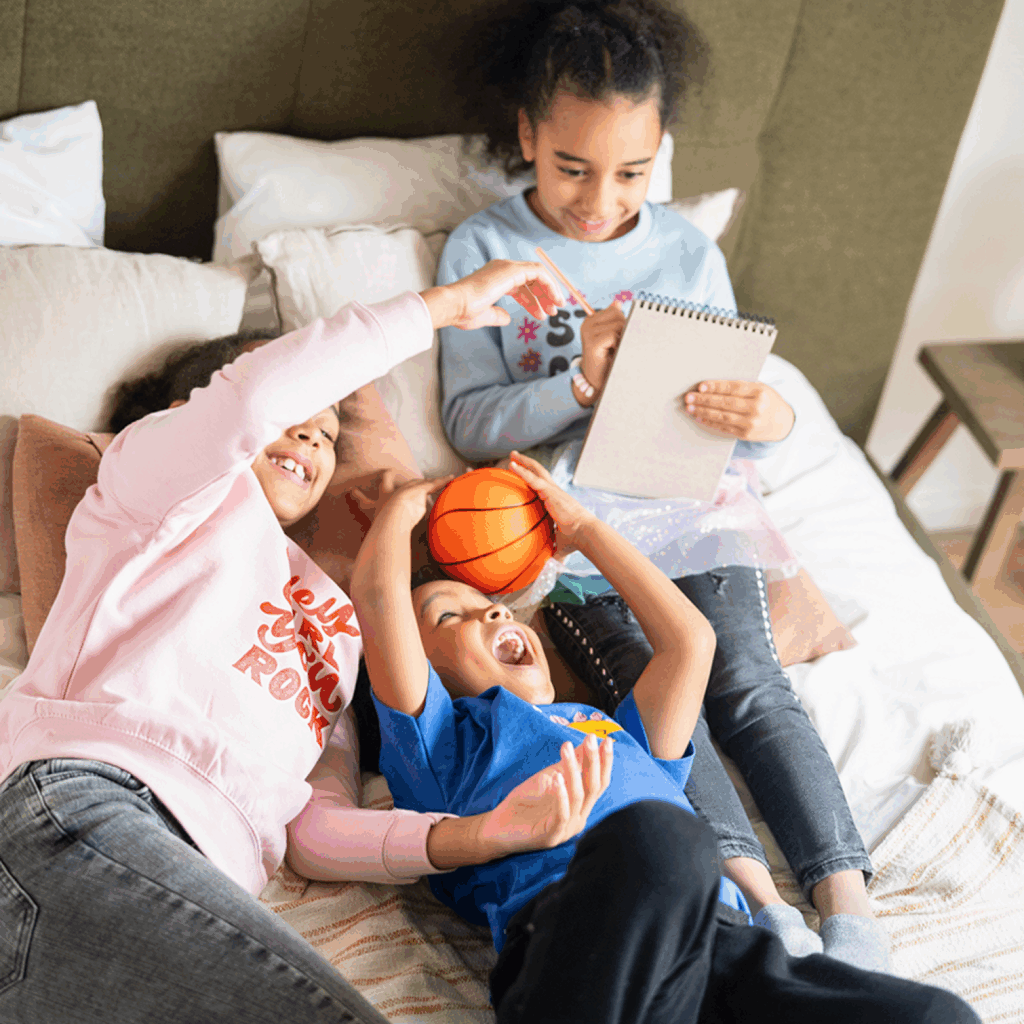 What are the essential back to school supplies Three children (two girls, one boy) are playing on top of a bed.