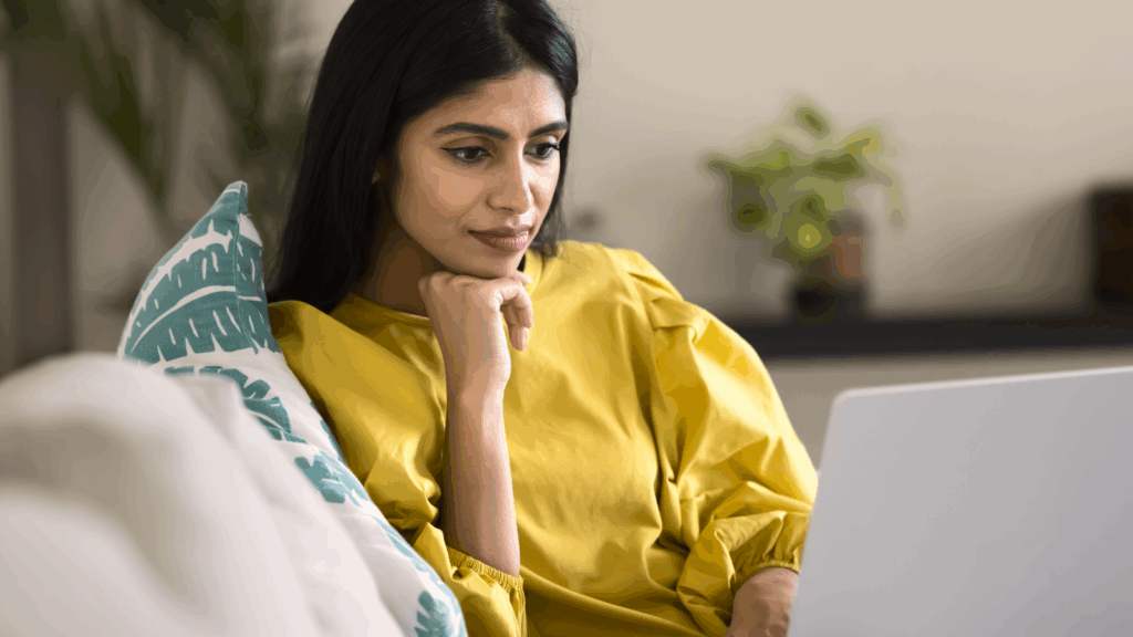 A woman is reading from a laptop screen.