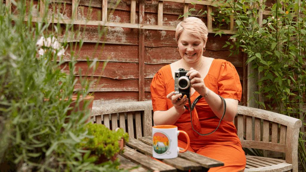 Why Print on Demand is a great way to make a living without a job A young smiling woman taking a picture of a custom mug for her print-on-demand business.