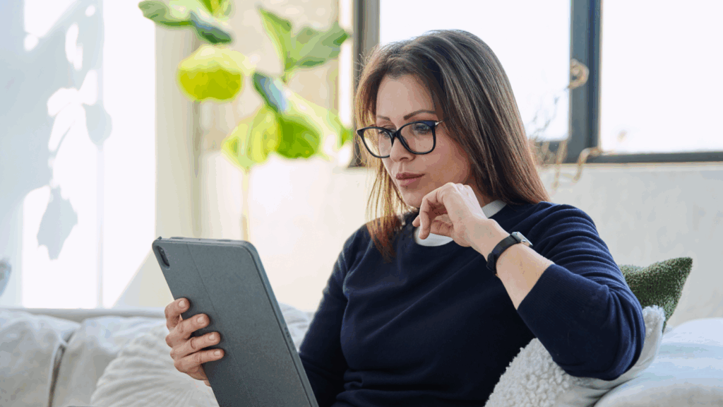 A woman is using a tablet to read the latest on Canada tariffs.