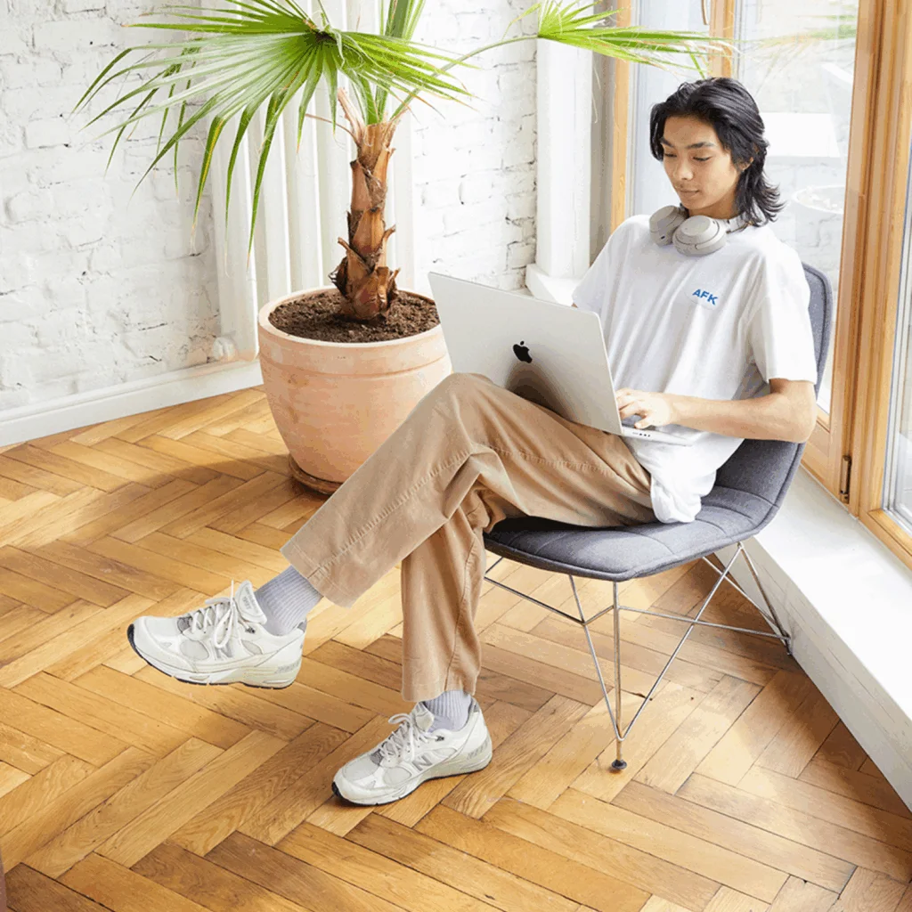 A young man is sitting in a chair and using a laptop to start an online store for a nonprofit.