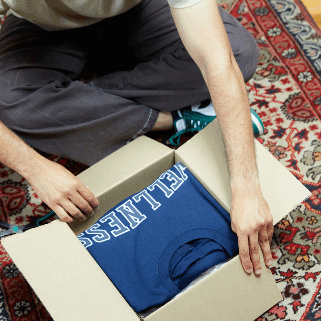 A man is taking out a hoodie from a delivery box.