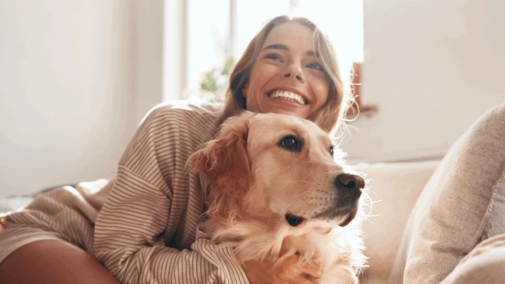 A smiling woman is petting a dog.