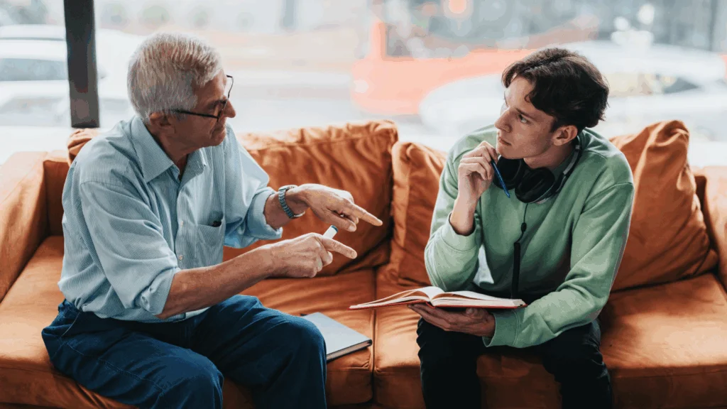 A young man is talking to an older man.