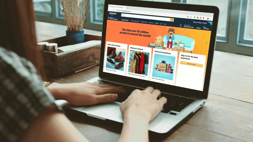 A woman is sitting in front of a laptop with Amazon’s homepage on the screen.
