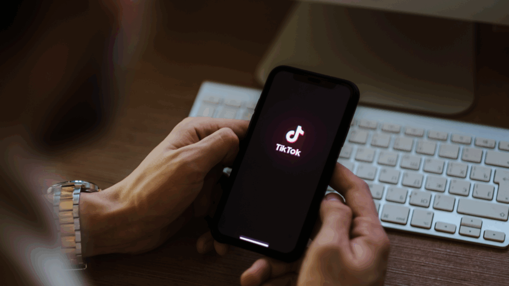 A person is holding a mobile phone with the TikTok app loading screen.