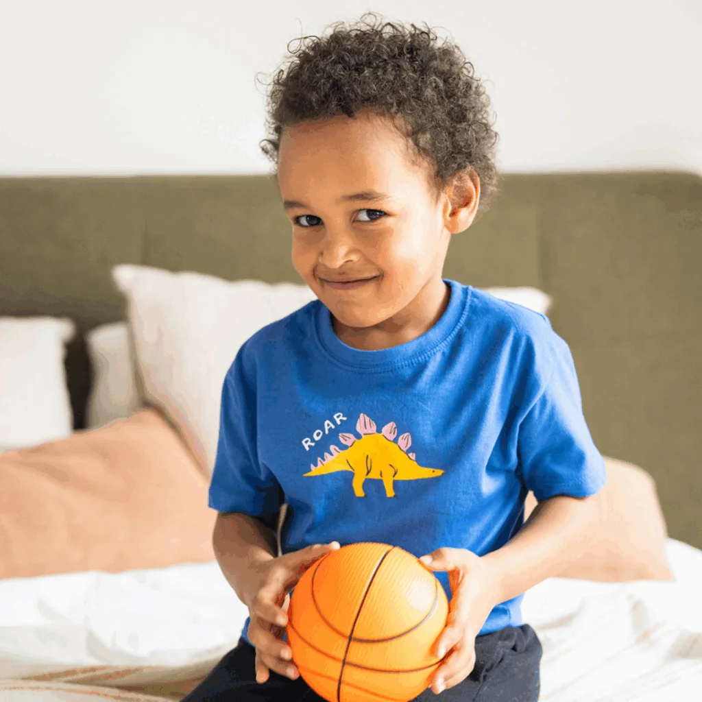 A child is holding a basketball and looking in the direction of the camera.