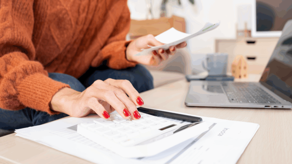 A woman calculates with a calculator while holding a piece of paper in her other hand.