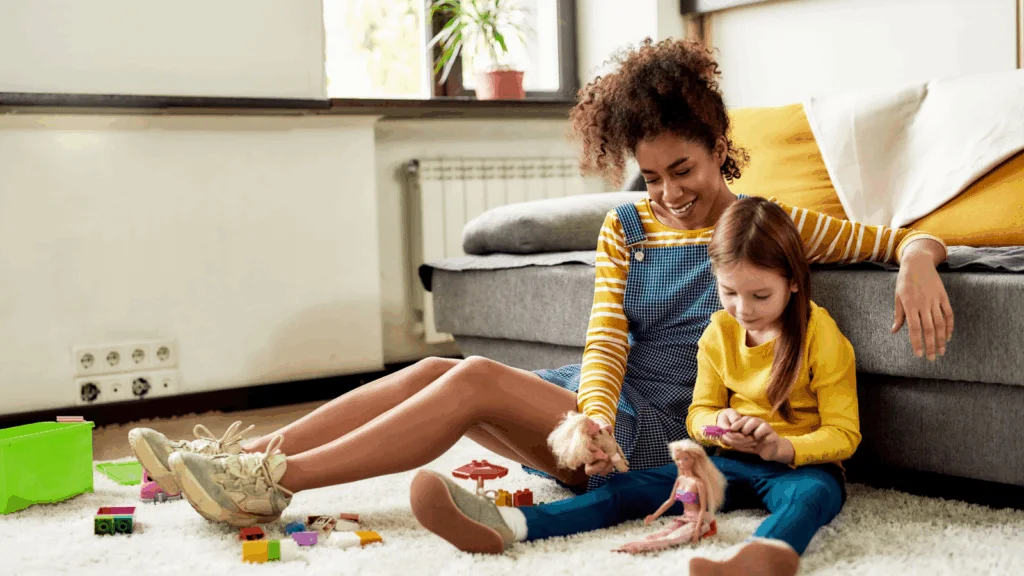 A woman babysitting a child, playing together on the ground.