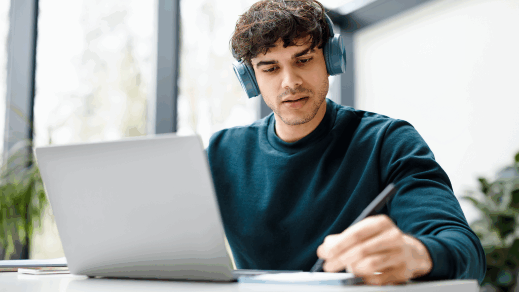 A man with headphones focused on his laptop, engaged in work or study.