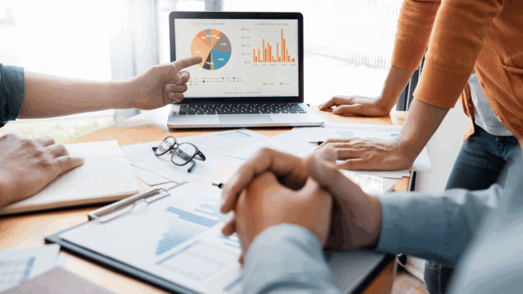 A group of people (only hands shown) are discussing and analyzing different data.