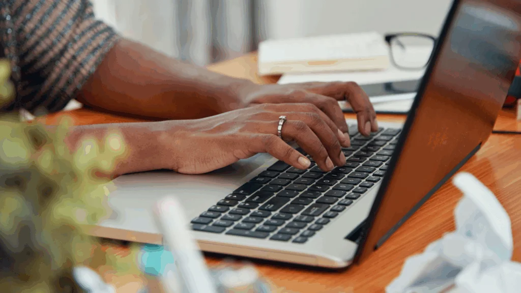 A woman is typing on a laptop keyboard.