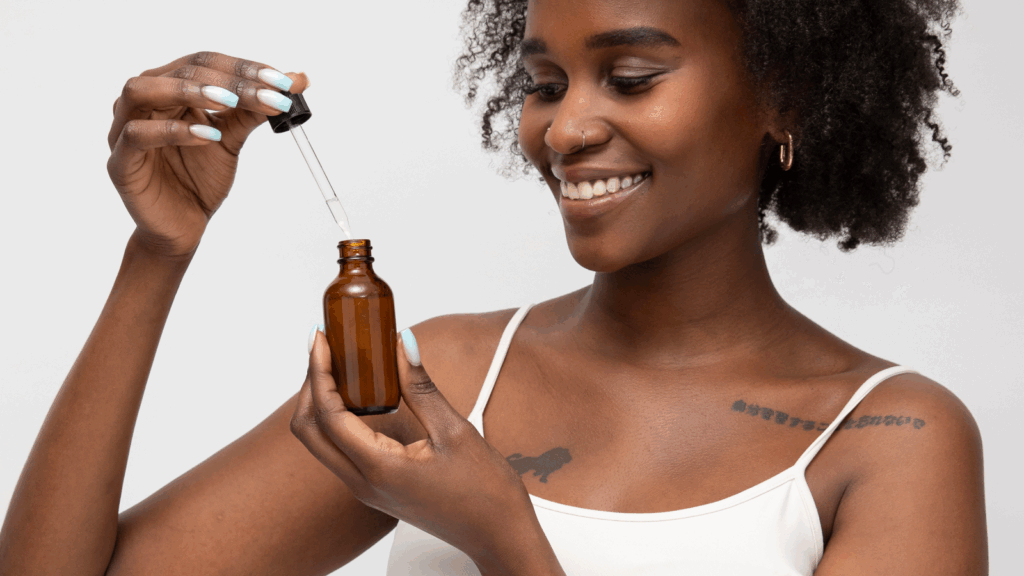 A woman holding a brown oil bottle, showcasing its label and contents in a well-lit setting.