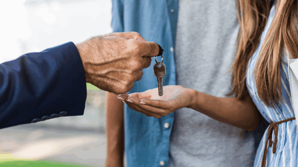 A man is handing a key to a woman, symbolizing a transfer of responsibility or access.