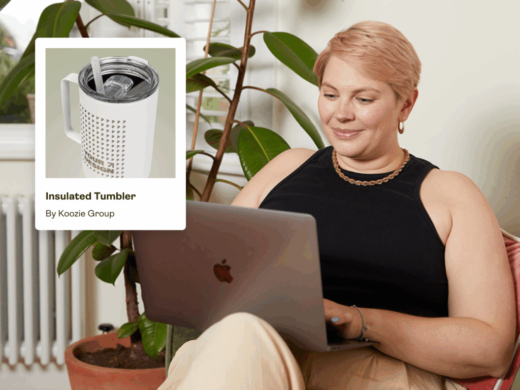 How to engrave glass with Printify A woman is sitting in a chair and using a laptop to order engraved products with print-on-demand.