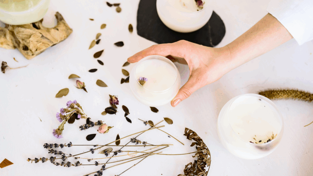 A person holds a cup filled with liquid and adorned with dried flowers.