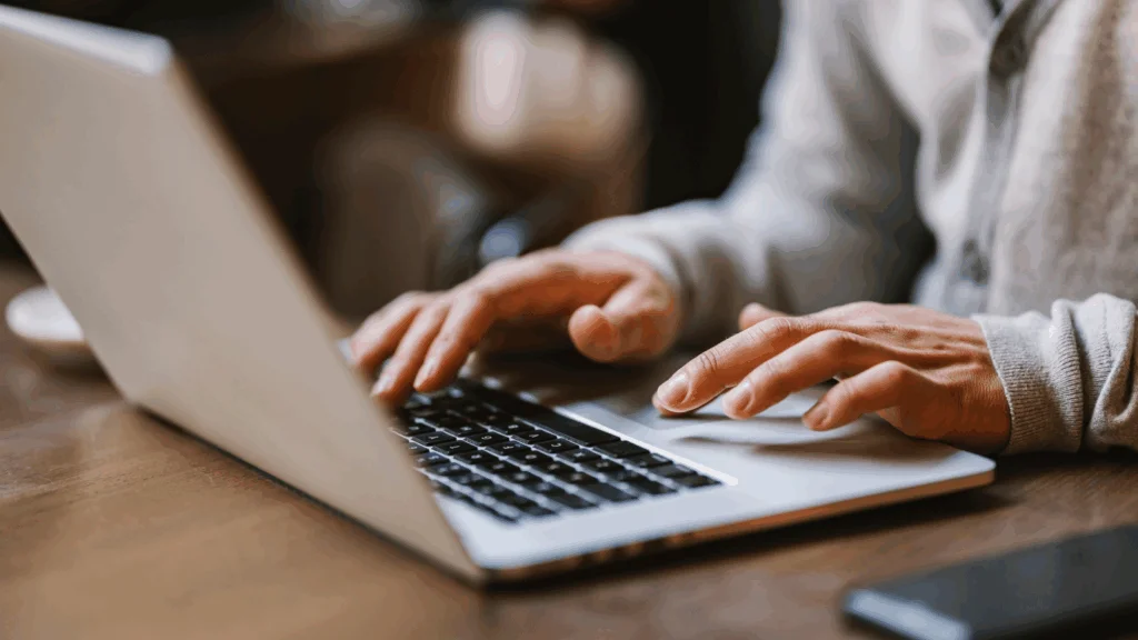 A person focused on typing on a laptop computer, with hands positioned over the keyboard.