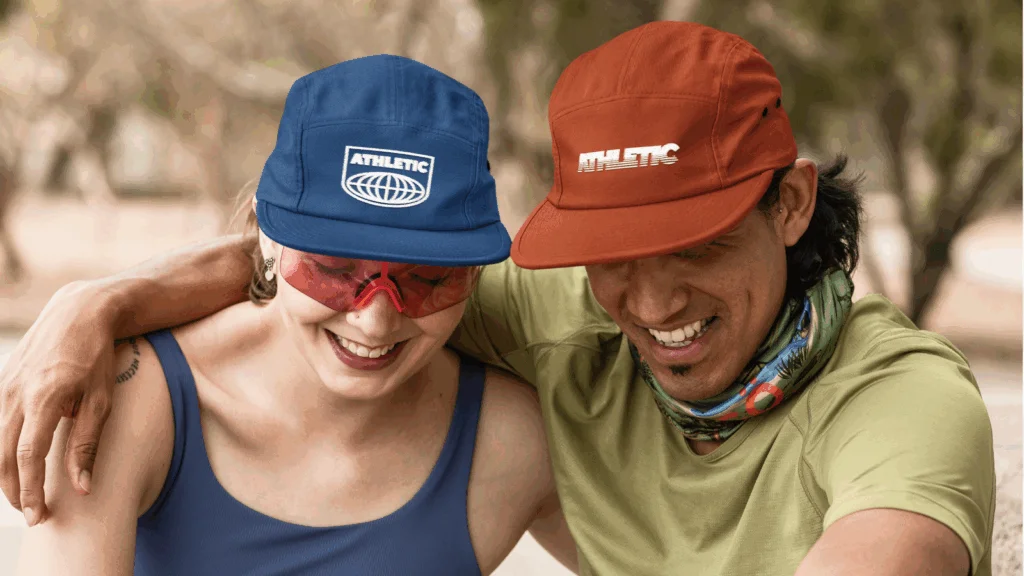 Two smiling individuals wearing hats, standing close together, exuding a cheerful and friendly atmosphere.