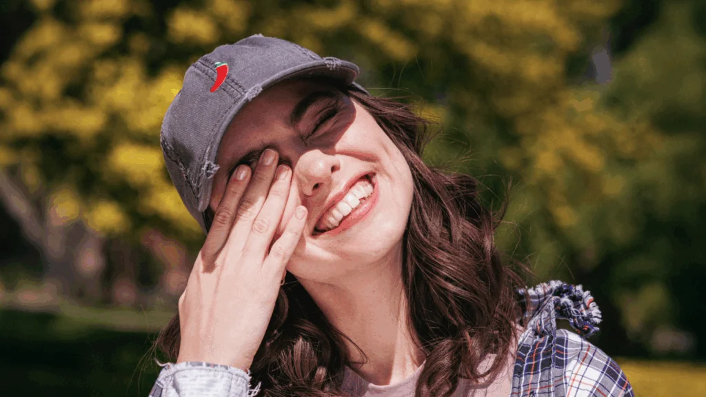 A woman wearing a stylish hat smiles warmly at the camera.