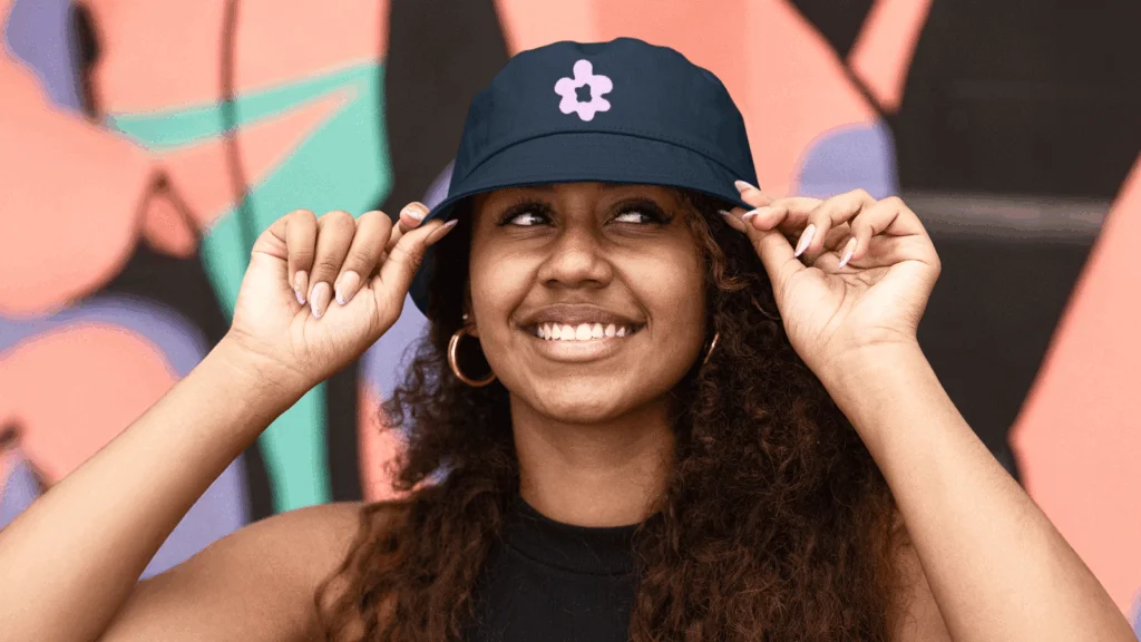 A woman wearing a purple hat adorned with a pink heart, smiling at the camera.