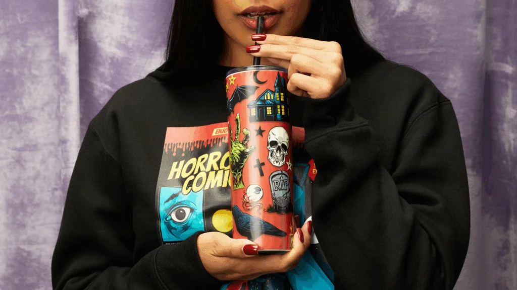 Bold colorful patterns Tumbler design ideas A woman with dark hair in a black sweatshirt holds a cup, smiling softly at the camera.