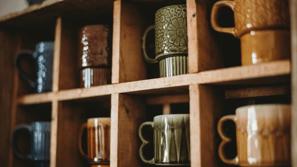 A wooden shelf displaying a variety of colorful coffee mugs arranged neatly.