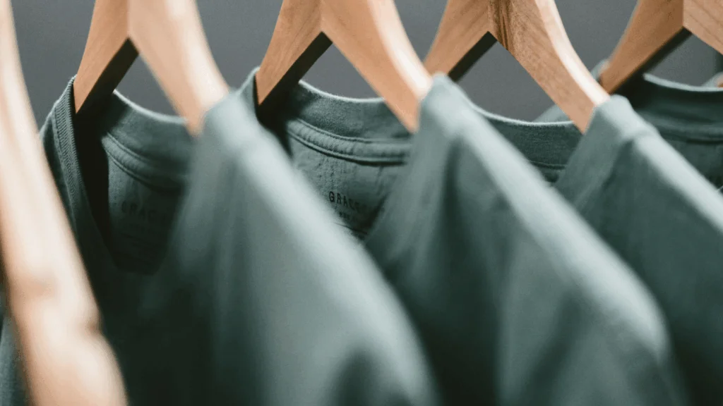 A row of green t-shirts neatly displayed on a clothing rack.