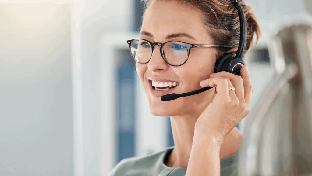A woman with glasses and a headset is engaged in a phone conversation.