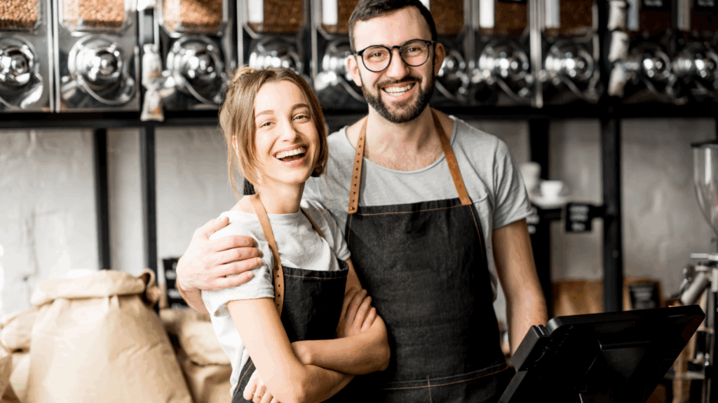 A couple stands together in front of a coffee shop, smiling and enjoying their time outdoors.