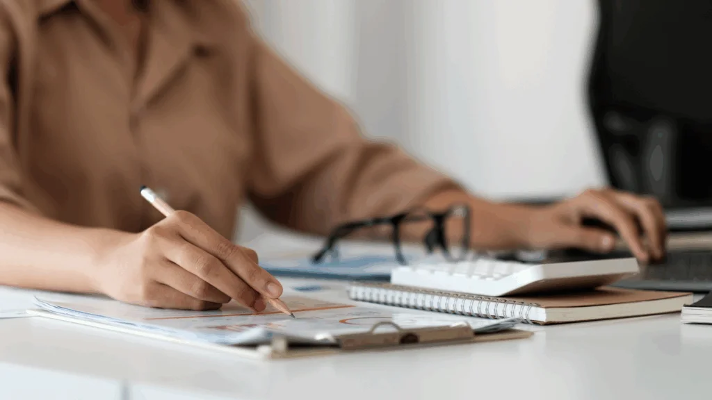 A woman writes on a piece of paper with a pen, focused on her task.