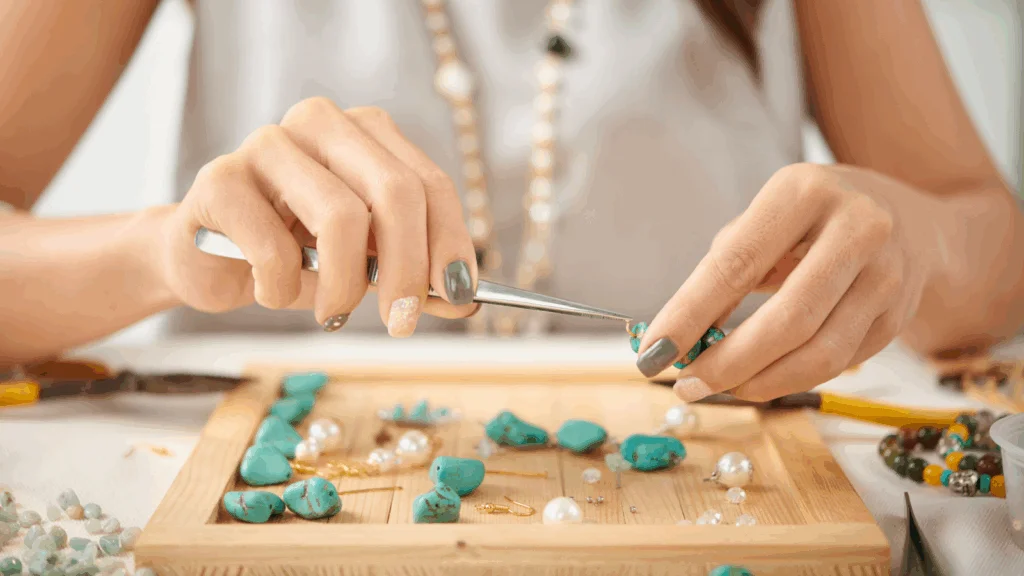 A woman carefully crafts jewelry, using scissors to cut materials with precision and focus.