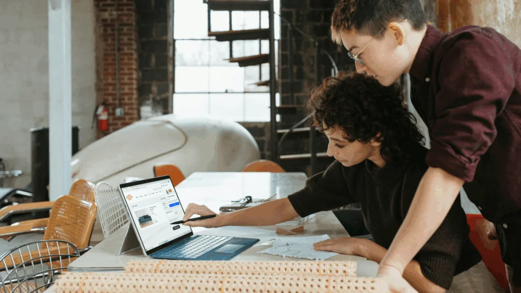 Two colleagues collaborating on a laptop in a modern office setting.