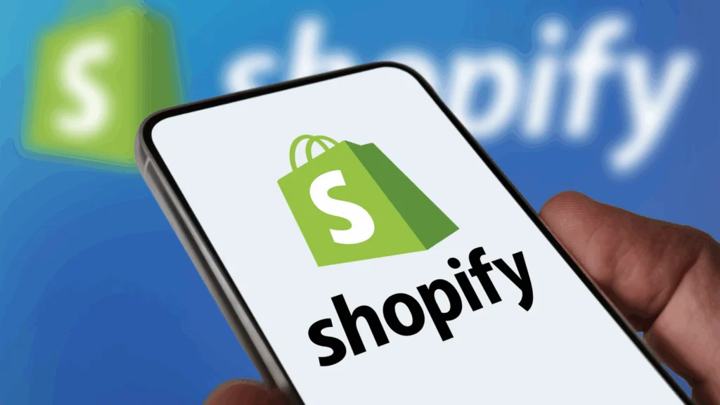 eCommerce and online store platforms A person holding a phone with a Shopify logo on it.