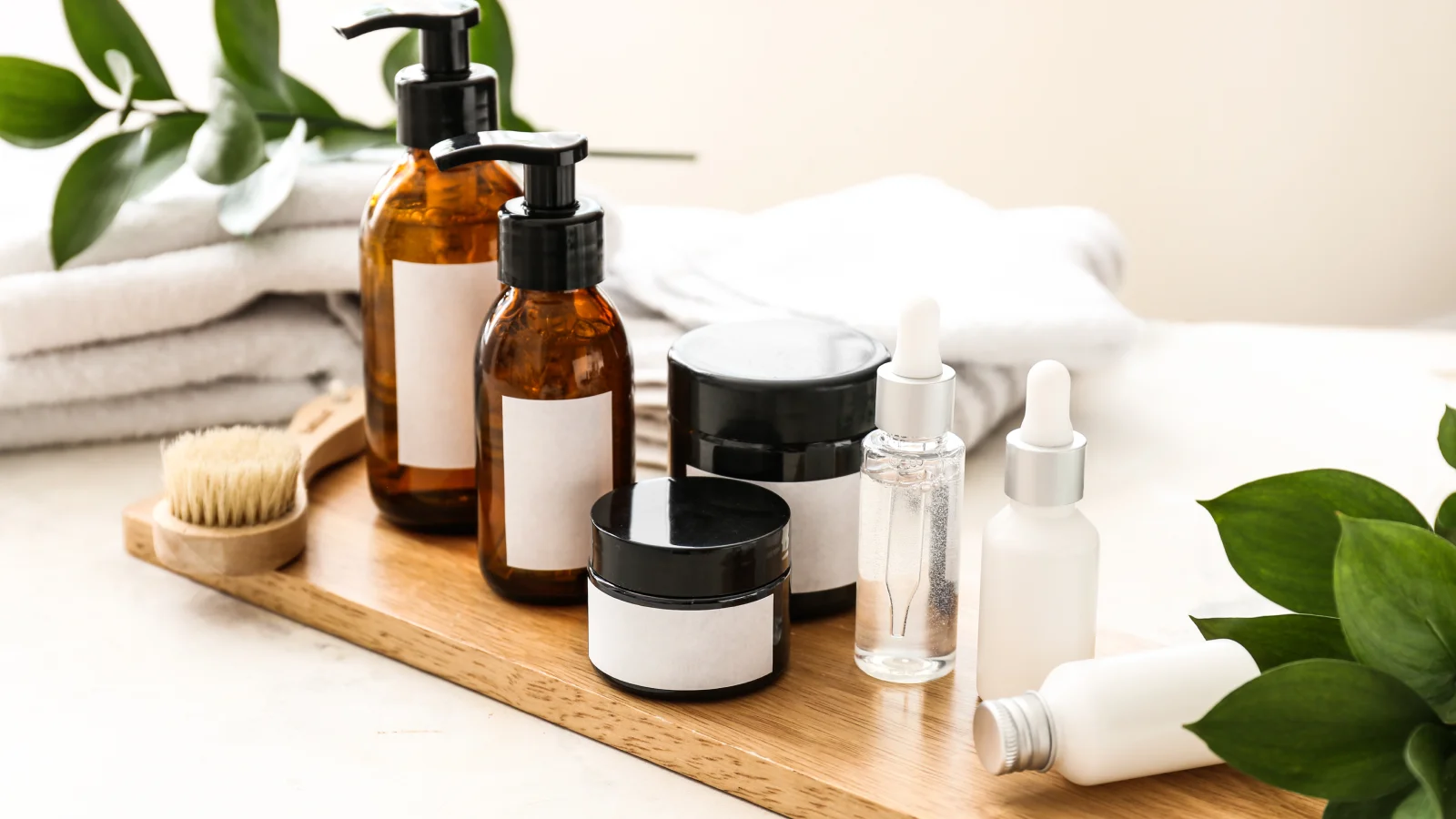 A wooden tray displaying an assortment of cosmetic products, including bottles, jars, and applicators.