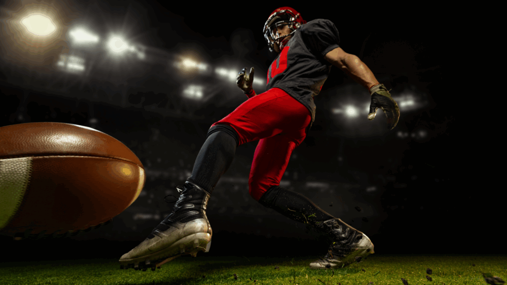 American football player in uniform kicking a football on the field during a game.