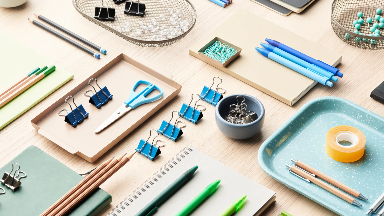 A variety of office supplies, including pens, paper, and a stapler, arranged neatly on a wooden desk.