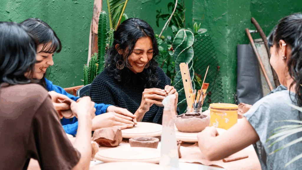 A group of women sits around a table, engaged in pottery-making, showcasing creativity and collaboration