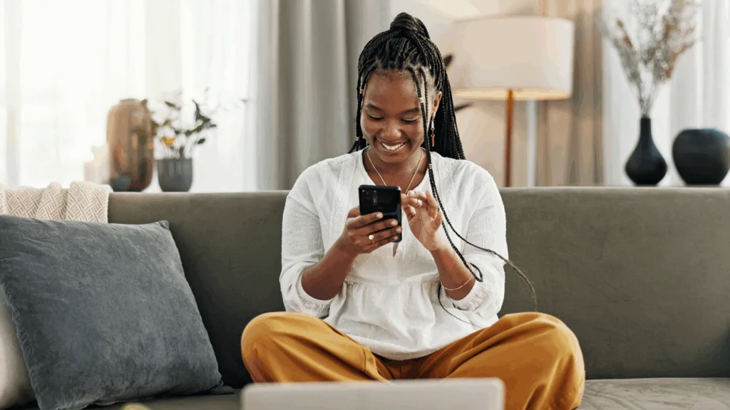 A young woman at home, focused on using her smartphone.