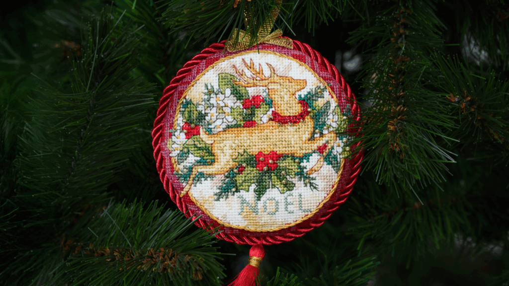 A cross-stitch ornament featuring a detailed deer design, showcasing intricate stitching and vibrant colors.