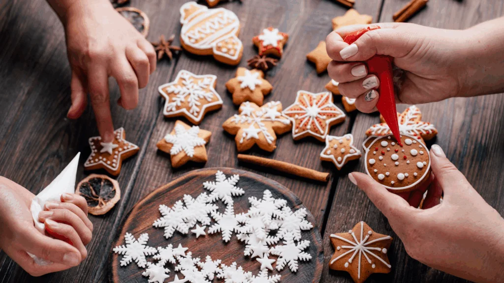 Hands decorate Christmas cookies with icing on a dark wooden table. Cookies shaped like stars and snowflakes.