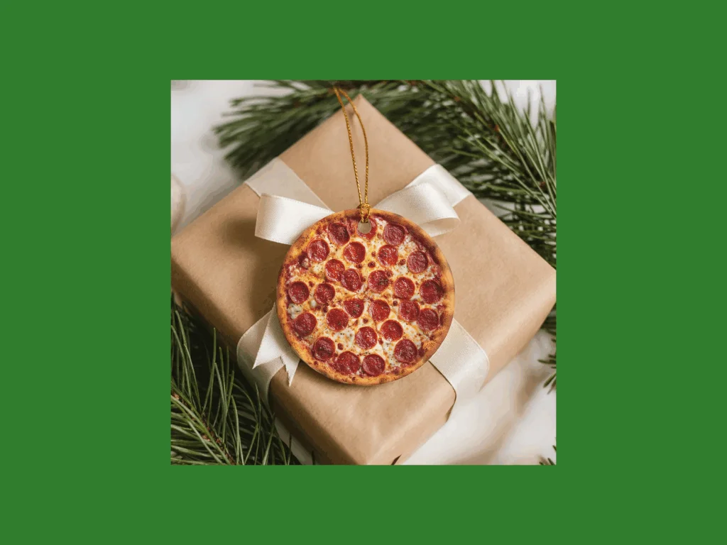 A round ornament with a pepperoni pizza print hangs from a ribbon on a brown wrapped gift.