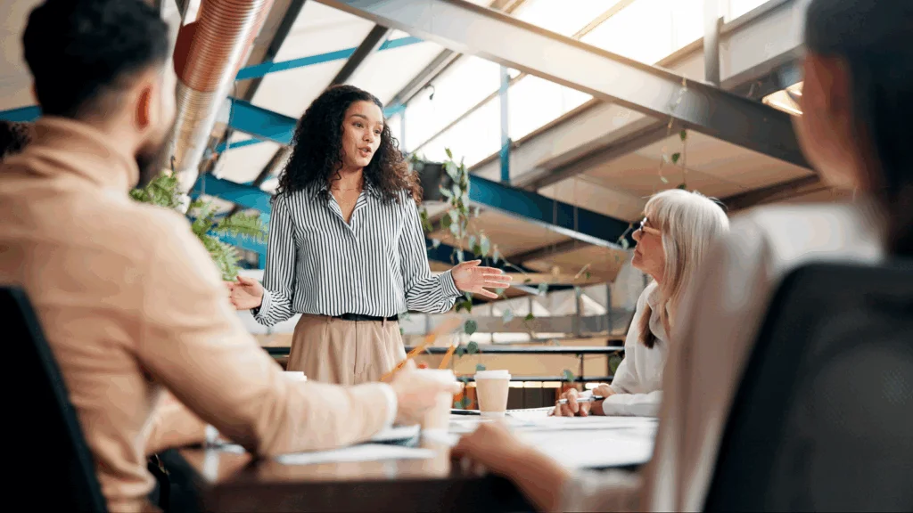 A woman presents to an audience, engaging them with her speech and visual aids.