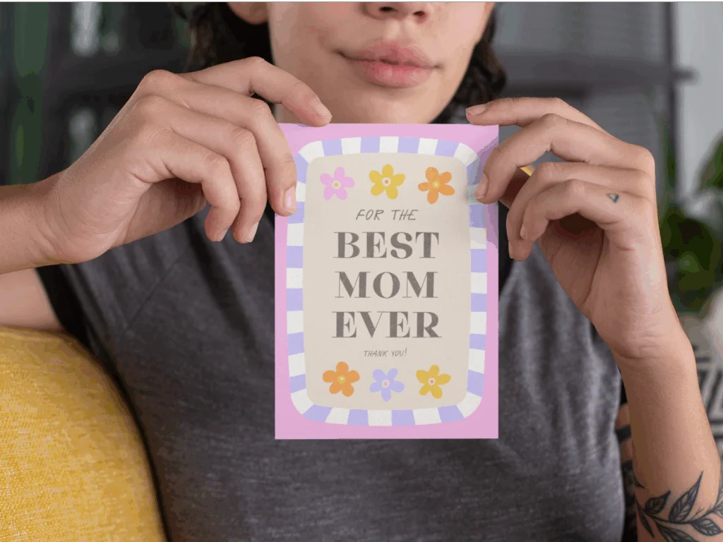 A woman proudly holds a card that reads "Best Mom Ever," smiling warmly at the camera.
